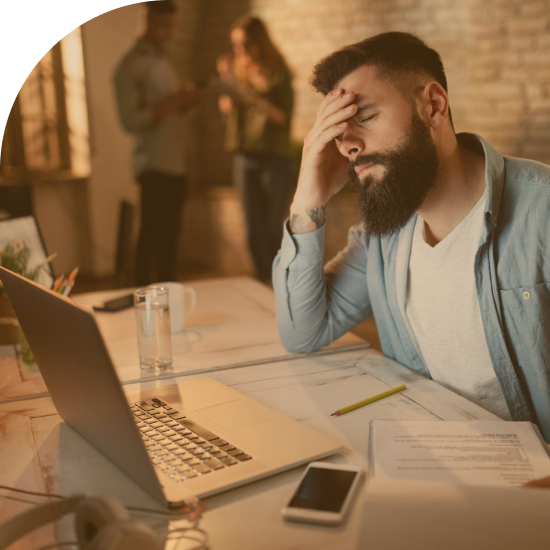 exhausted-businessman-holding-his-head-pain-while-working-late-office